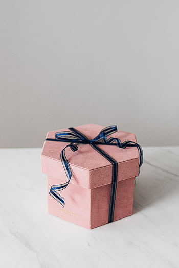A minimalist pink hexagon gift box with a navy ribbon on a marble surface, perfect for celebrations. HD phone wallpaper