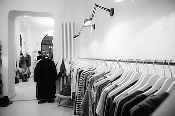 Stylish black and white interior of a boutique with clothes on racks, showcasing modern fashion. HD wallpaper
