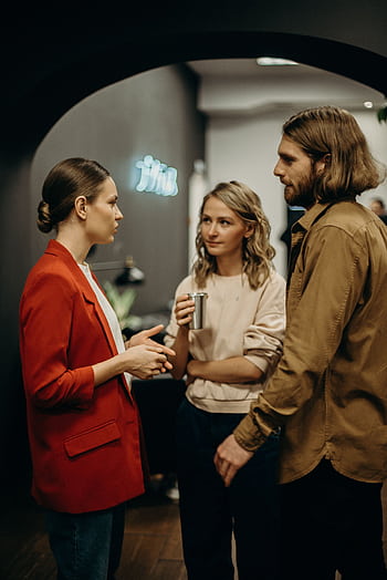 Three colleagues having a discussion in a modern office setting. HD phone wallpaper