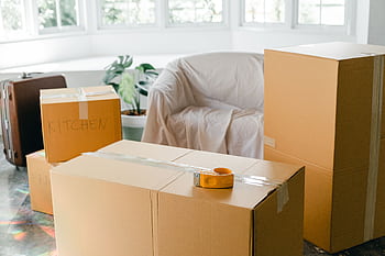 Cardboard boxes labeled 'Kitchen' in sunlit living room, ready for relocation. HD wallpaper