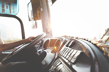 A bus driver navigating the city streets during a sunny day, focusing on the road. HD wallpaper