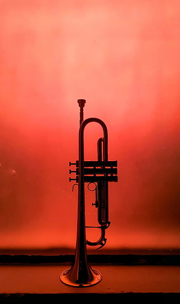 A single trumpet stands silhouetted against a vivid orange background, creating a dramatic musical . HD phone wallpaper