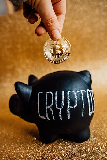 A hand places a Bitcoin into a piggy bank labeled 'Crypto', symbolizing savings and investment. HD phone wallpaper
