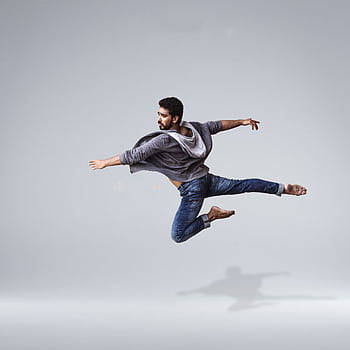 A male contemporary dancer in casual wear leaping gracefully in mid-air, showcasing agility and flexibility. HD phone wallpaper