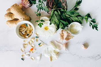 A flatlay of herbal supplements with fresh ginger, garlic, and leaves. HD wallpaper