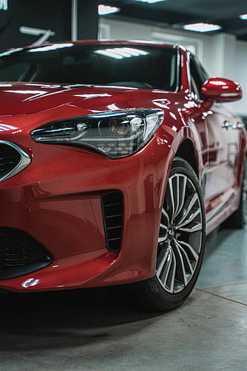 Detailed view of a red sport car showcasing sleek design and shiny finish indoors. HD phone wallpaper