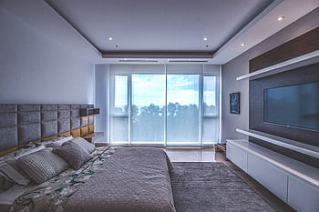 Spacious luxury bedroom with a modern design, featuring a large window and a wall-mounted TV. HD wallpaper