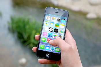 Close-up of a hand holding a smart outdoors near a river. HD wallpaper
