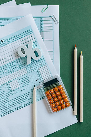 Flat lay of tax documents, calculator, and pencils on green surface. HD phone wallpaper