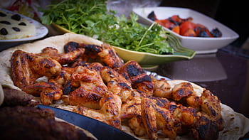 A close-up of grilled chicken wings served with fresh herbs and vegetables, perfect for culinary presentations. HD wallpaper