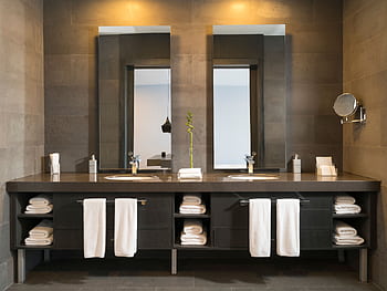 Stylish modern bathroom interior with twin mirrors and towels arranged over sleek dark countertops. HD wallpaper