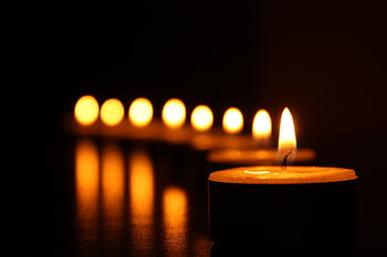 A close-up view of tealight candles reflecting a warm glow in the dark. HD wallpaper