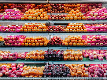 Colorful variety of fresh fruits neatly arranged on supermarket shelves, showcasing abundance and freshness. HD wallpaper