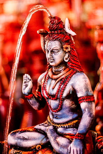 Close-up of a colorful Lord Shiva statue with water flow, capturing spiritual essence. HD phone wallpaper
