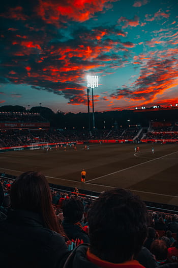 Dramatic sunset over a lively soccer game in a large stadium filled with spectators. HD phone wallpaper