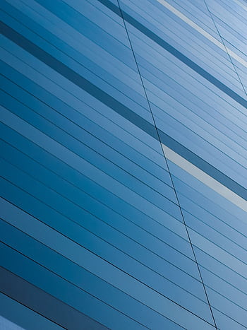 Abstract view of a modern blue glass building facade with geometric lines reflecting sunlight. HD phone wallpaper