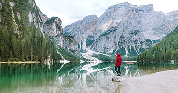 Person standing by the scenic Lake Braies with majestic Dolomite mountains reflected in the water. HD wallpaper