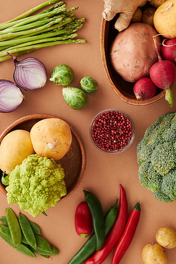 A colorful flat lay of fresh vegetables including asparagus, broccoli, and chili peppers on a brown surface. HD phone wallpaper