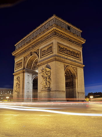 Elegant night shot of the Arc de Triomphe in Paris with light trails underneath, capturing its monumental beauty. HD phone wallpaper