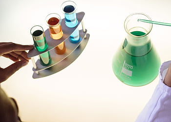 A vibrant science experiment involving colorful liquids in test tubes and a flask. HD wallpaper