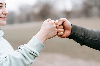Two people engage in a friendly fist bump outdoors, symbolizing unity and friendship. HD wallpaper
