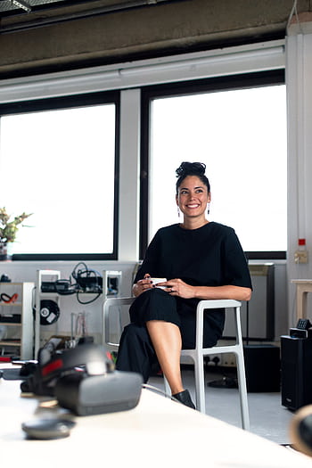 Confident young professional woman enjoying a coffee break in a modern office environment. HD phone wallpaper