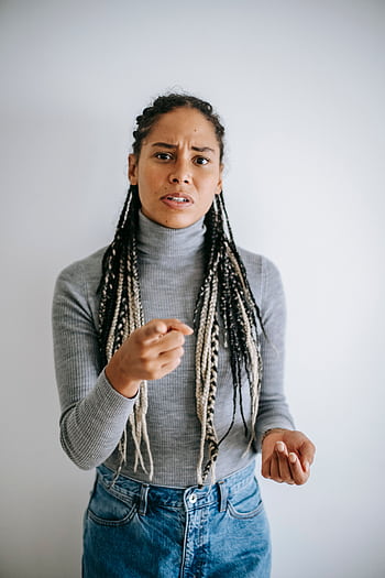 A woman with braided hair gestures emotionally against a gray background. HD phone wallpaper