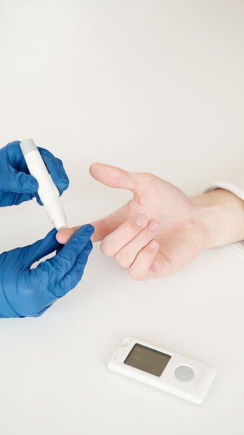 A healthcare professional tests blood sugar with a glucometer and lancet pen in a medical setting. HD phone wallpaper