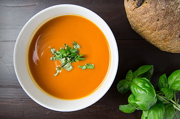 Delicious homemade tomato soup served with basil leaves and rustic bread. HD wallpaper