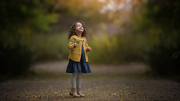 Smiley Cute Little Girl Is Looking Up Wearing Yellow Coat Blue Dress Standing In Blur Nature Background Cute HD wallpaper