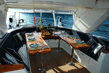 Luxurious yacht deck with an elegantly set dining table overlooking the tranquil sea. HD wallpaper