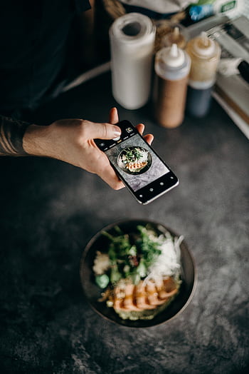 A person graphing a beautifully plated Asian dish with a smart camera. HD phone wallpaper