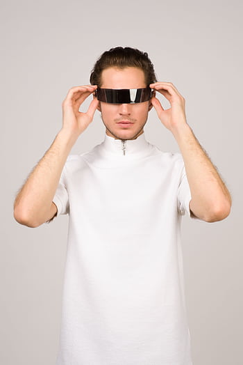 A young man in a stylish white shirt poses with futuristic VR glasses, embodying modern tech fashion. HD phone wallpaper