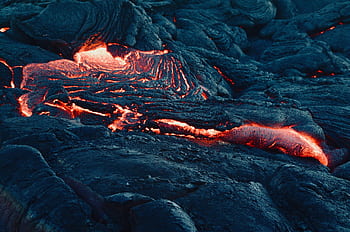 A mesmerizing view of flowing lava on a volcanic landscape, capturing the intense heat and texture. HD wallpaper