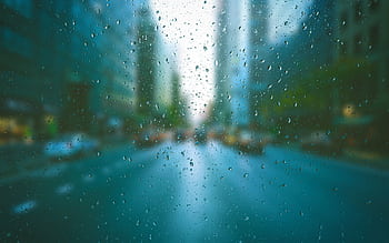 Blurred city scene through raindrop-covered window, creating a tranquil urban mood. HD wallpaper