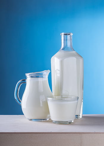 Minimalist still life of fresh milk in glassware against a blue background. HD phone wallpaper