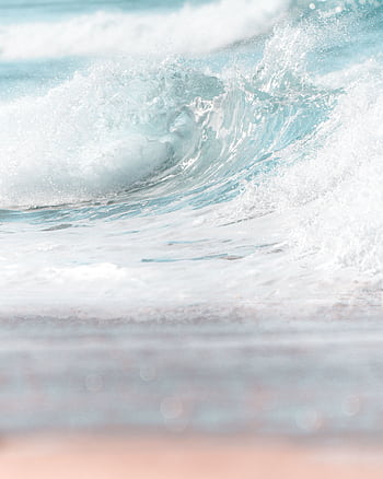 Close-up view of a serene ocean wave hitting a sandy beach, highlighting the tranquil beauty of nature. HD phone wallpaper
