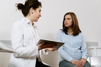 A doctor consults with a pregnant patient discussing healthcare options in a medical facility. HD wallpaper