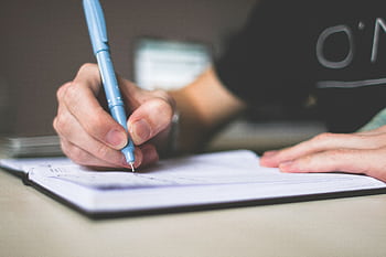 Close-up of hand writing in notebook using a blue pen, focus on creativity. HD wallpaper