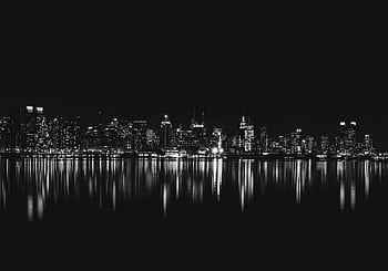 Captivating black and white view of New York City skyline reflecting on water at night. HD wallpaper
