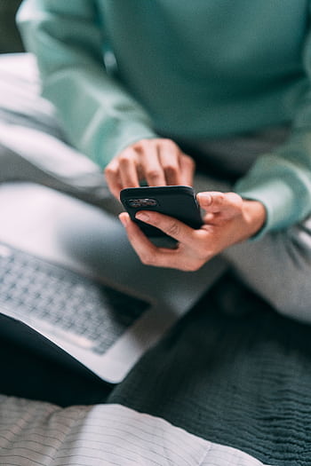 A person using a smart and laptop on a bed indoors, capturing a modern lifestyle moment. HD phone wallpaper
