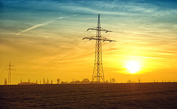 Silhouetted power lines stretch against a dramatic sunset sky, symbolizing energy and tranquility. HD wallpaper