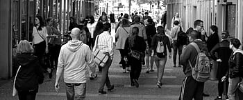 A bustling street scene capturing diverse pedestrians walking outdoors in an urban setting. HD wallpaper