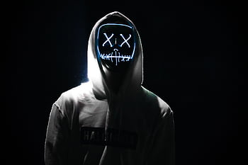 A person in a hooded sweatshirt wears a glowing LED mask in a dark, mysterious setting. HD wallpaper