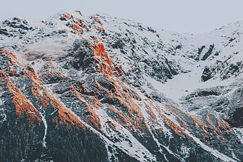 Stunning view of sunlight illuminating snow-capped mountain peaks, perfect for adventure and nature enthusiasts. HD wallpaper