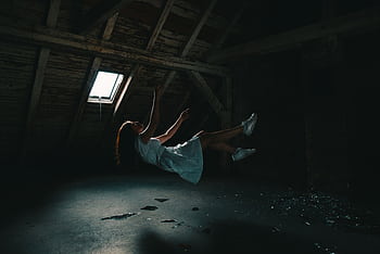 A surreal graph of a woman in a white dress floating in an abandoned attic, capturing a sense of mystery. HD wallpaper
