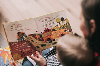 A mother and toddler sharing a story from an illustrated children's book indoors. HD wallpaper