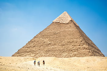 Iconic Giza Pyramid with riders on camels under bright daylight, capturing Egyptian desert landscapes. HD wallpaper