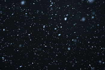 A mesmerizing view of snowflakes falling against a dark, starry night sky. HD wallpaper
