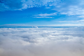 A stunning aerial view of fluffy clouds under a bright blue sky, captured in daylight. HD wallpaper